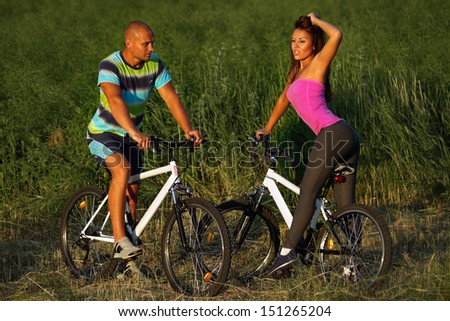 Sport couple riding bikes in field