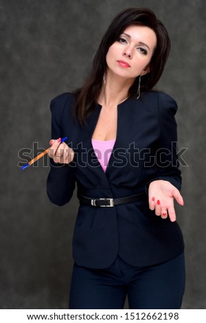 Portrait of a brunette manager woman in a business suit on a gray background. Great makeup and beautiful hair. Standing right in front of the camera in various poses.