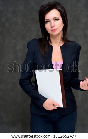 Portrait of a brunette manager woman in a business suit on a gray background. Great makeup and beautiful hair. Standing right in front of the camera in various poses.