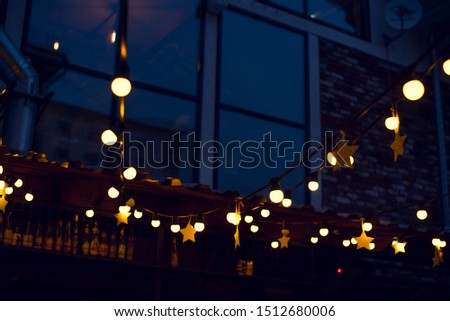Garland with lights and stars in a street bar in the evening.