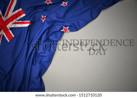 waving colorful national flag of new zealand on a gray background with text independence day. concept