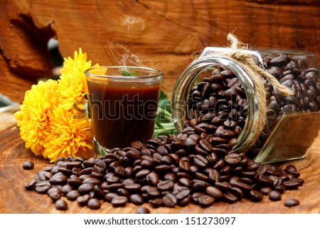 Roasted coffee beans on wood and black coffee.