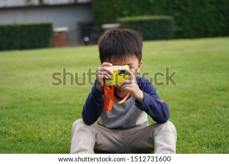 FRONT VIEW OF YOUNG KID TAKING PHOTO OUTDOOR