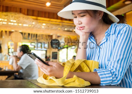 young asian woman with hat use smart phone in Coffee shop,