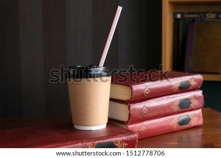 Classic book and modern drink on the background of the bookshelf. Against the background of a pleated tree and retro wallpaper.