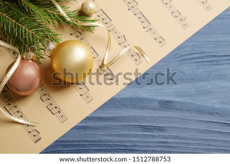 Flat lay composition with Christmas decorations and music sheets on blue wooden table. Space for text