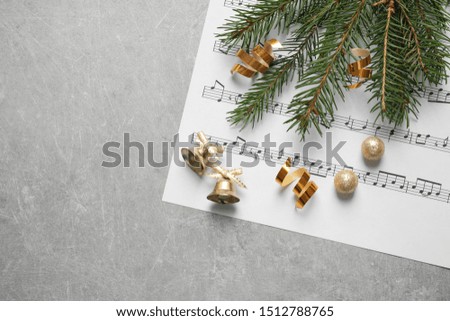Christmas decorations and music sheet on grey stone table, flat lay with space for text