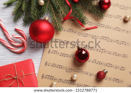 Flat lay composition with Christmas decorations and music sheets on white wooden table