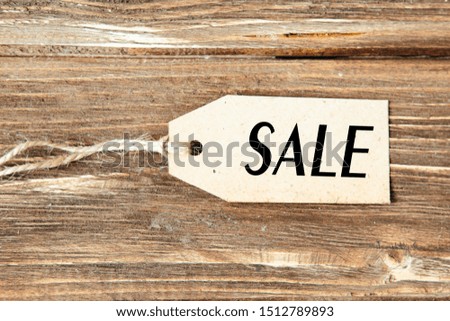 Blank label with word SALE on wooden background One paper blank tags with word SALE with rope on wooden background.