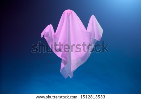 Picture of halloween pink ghosts from white fabric on blue background