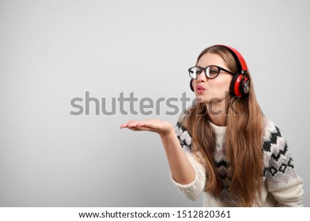 Young woman listening to music with headphones on grey background, space for text