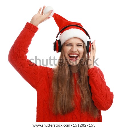 Young woman in Santa hat listening to Christmas music on white background