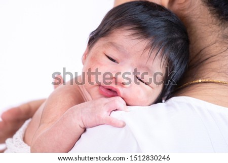 Close up beautiful young Asian mother hold happy tiny adorable newborn baby girl 0-1 month on shoulder with caring and love, lifestyle health care newborn baby at home concept on white background