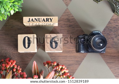 January 6, Date design with Number cube, a flower and camera on Diamond wood background.