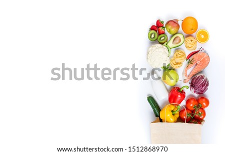 Healthy food in paper bag fruits, vegetables, milk, pasta and fish on white background. Healthy food background. Shopping food supermarket, meal and nutrition plan concept. Top view and copy space