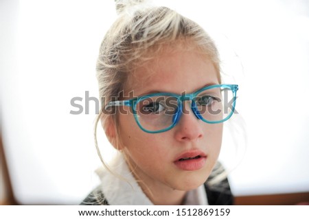 cute crying little girl in glasses with face wet of tears