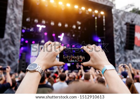 Recording concert by smartphone. Mobile phone in raised hands