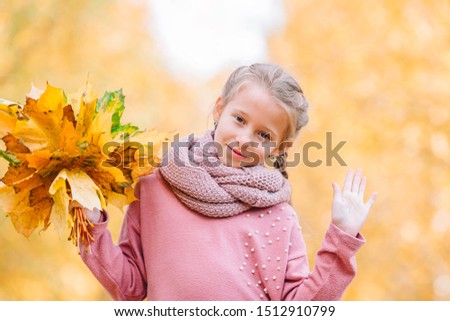 Portrait of adorable little girl with yellow leaves bouquet in fall at autumn park outdoors