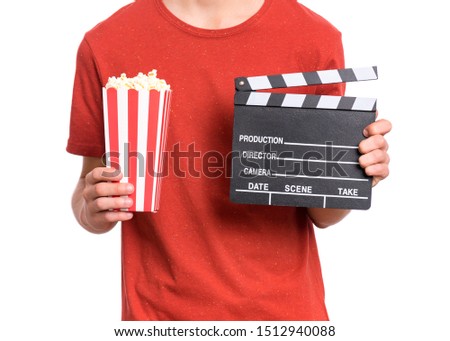 Teen boy hands with cinema clapper board and popcorn bucket, isolated white background. Child preparing to watch the film while holding movie clapper and popcorn. Close-up photo.