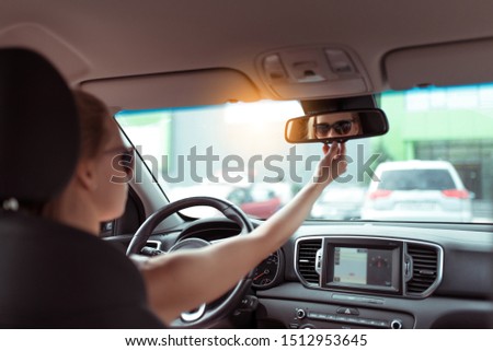 woman car summer city parking lot, looks rear view mirror, parks reverse, looks rear seat, checks children in back rows of seat. Background car interior, steering wheel navigation display