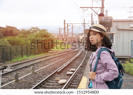 Beautiful tourist hold camera with hat and backpack on train platform.