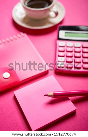 Closeup of calculator and open notebook with pencil on intense pink desk