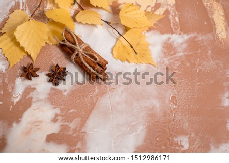 Dry autumn yellow birch leaves on a concrete background. Cozy autumn concept Flat lay. copy space. Cinnamon and cardamom for hot tea or cappuccino