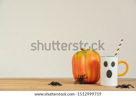 Accessories of decorations Happy Halloween day background concept.Cup of drink with pumpkin object to party season with spider on modern rustic brown & white backdrop at home office desk studio.