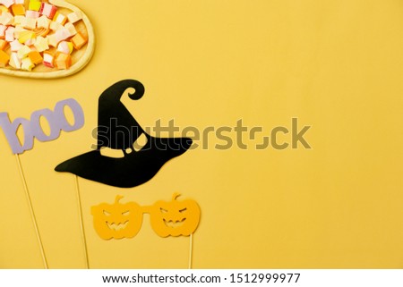 Table top view aerial image of decoration Happy Halloween day background concept.Flat lay accessories essential object to party the photo prop & sweet candy on yellow paper.Space for creative design.
