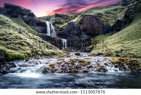 Typical Icelandic scenery. Fresh green hills and waterfall.  Picture of wild area. Iceland. Amazing nature landscape with colorful sky during sunset.
