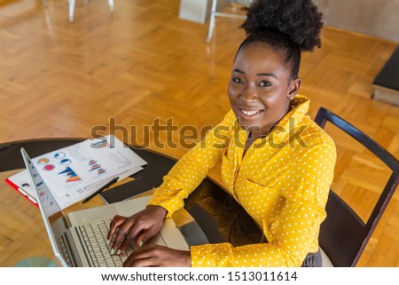 Smiling businesswoman using computer in office. Female businessmen work at the desk about accounting and business plan analysis. Black woman talking on phone at her desk in office. Graphs and charts