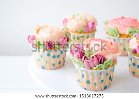 Cupcakes with colorful cream flowers on white background. Picture for a menu or a confectionery catalog.