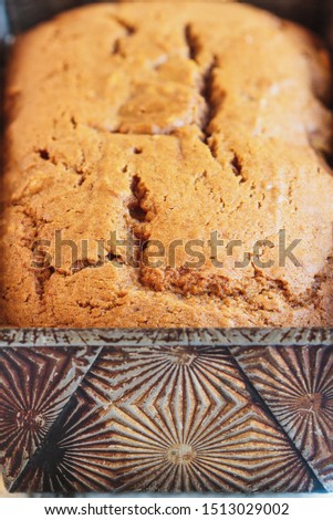 Abstract of extreme close up of fresh baked homemade pumpkin bread in an antique envelop loaf pan. Selective focus on foreground with blurred background.