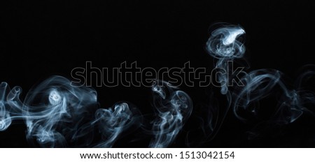 Background image of a wisp of smoke on a dark background. The texture of the flowing smoke. Graphic resources dark backdrop. Texura of white clouds of fog. Curls of smoke frozen in motion.