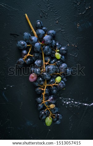 Bunch of blue grapes on dark blue background. Vertical image, top view with copy space