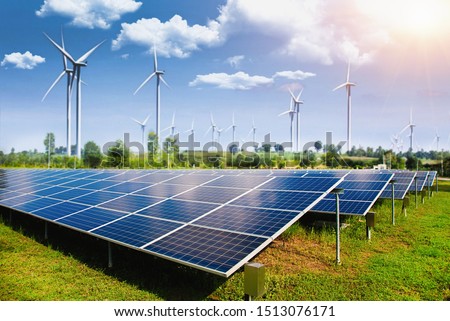 Solar panel with wind turbines against mountains and sky as background - image