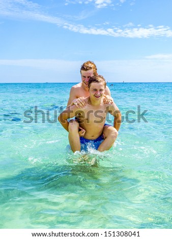 handsome teen have fun playing piggyback in the ocean