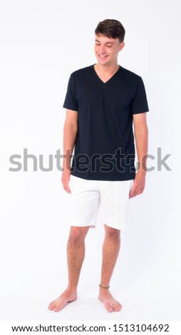 Full body shot of happy young handsome man thinking and looking down
