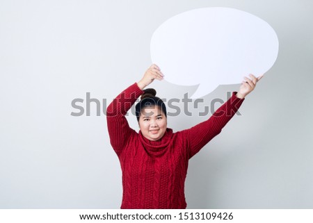 Attractive asian Woman in red sweater holding showing blank speech bubble on light gray background, copy space for text