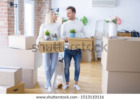Young beautiful couple with dog moving cardboard boxes at new home