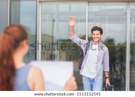 Long-awaited date. Young woman with name board meeting cheerful millennial guy in airport, free space