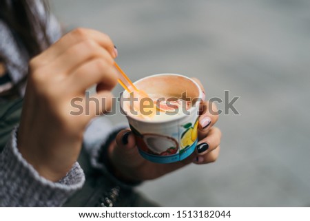Fruit ice cream in a paper glass eat with a spoon.