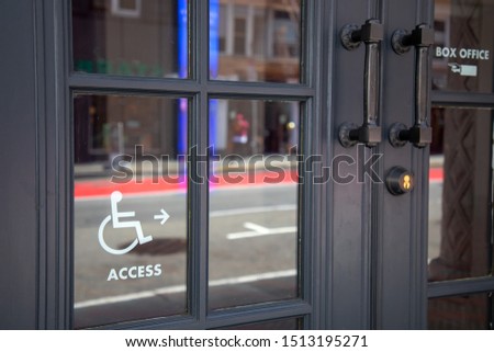 Handicapped access entrance sign on door glass at the entrance of the shop or restaurant.