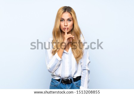Young blonde woman over isolated blue background showing a sign of silence gesture putting finger in mouth