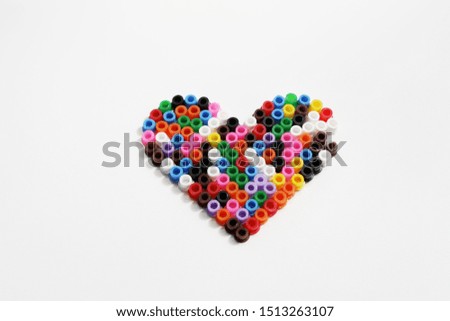 Heart made of colorful plastic pearls isolated on white