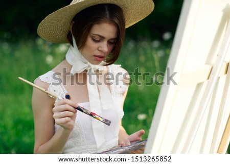 woman paints a painting with an easel in nature