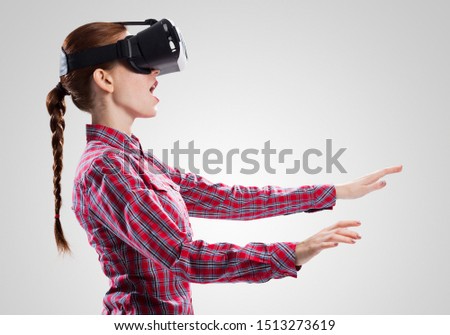 Young woman in checked shirt wearing virtual helmet against gray background