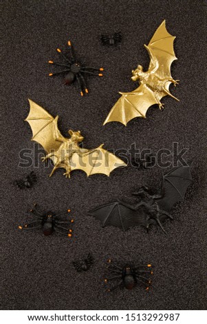 Top view of Halloween decoration with plastic black and golden bats over glitter background. Party, invitation, halloween decoration concept