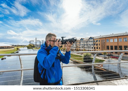Man photographer in blue jacket with digital camera taking pictures. 