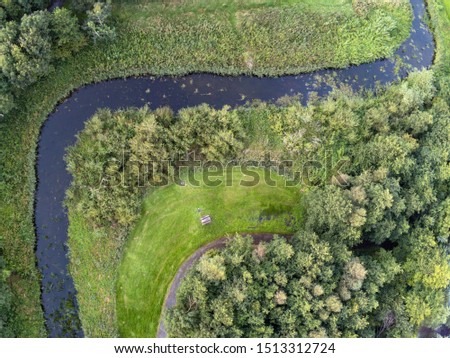 Creek in a park with ninety degree turn, Walking path, and forest. Aerial top view.